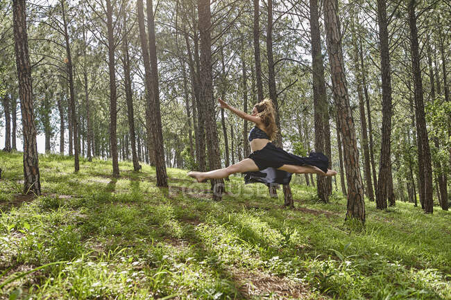 Descalço jovem mulher pulando no ar na floresta — Fotografia de Stock