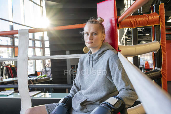 Portrait of a female boxer in gym sitting in ring corner — Stock Photo