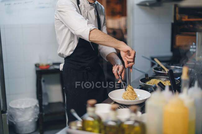 Chef preparando un plato de pasta en la cocina tradicional del restaurante italiano - foto de stock