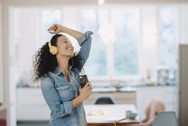 Femme heureuse écoutant de la musique, chantant et dansant, utilisant smartphone et écouteurs — Photo de stock