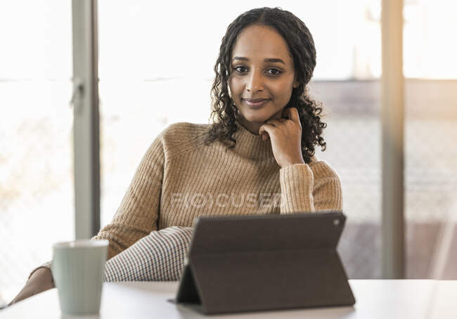 Portrait de jeune femme d'affaires souriante assise au bureau avec tablette — Photo de stock