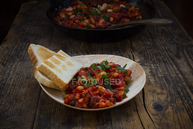 Vegane gebackene Nierenbohnen, weiße Bohnen, Tomaten und Petersilie auf einem umweltfreundlichen Teller aus Palmblättern — Stockfoto