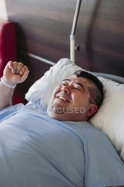 Портрет усміхненого пацієнта лежить у лікарняному ліжку. — стокове фото