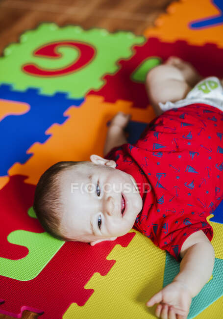 Портрет усміхненого хлопчика, що лежить на барвистому підлозі — стокове фото