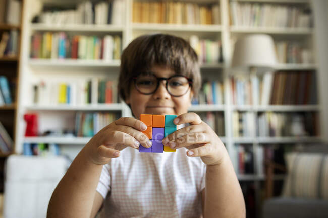 Sonriente niño sosteniendo cubo hecho de bloques de construcción - foto de stock