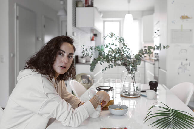 Porträt einer Frau, die am Küchentisch sitzt und Tee trinkt — Stockfoto