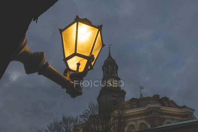 Deutschland, Hamburg, Tiefansicht von Straßenlaternen, die nachts gegen den Turm der St.-Michaels-Kirche leuchten — Stockfoto