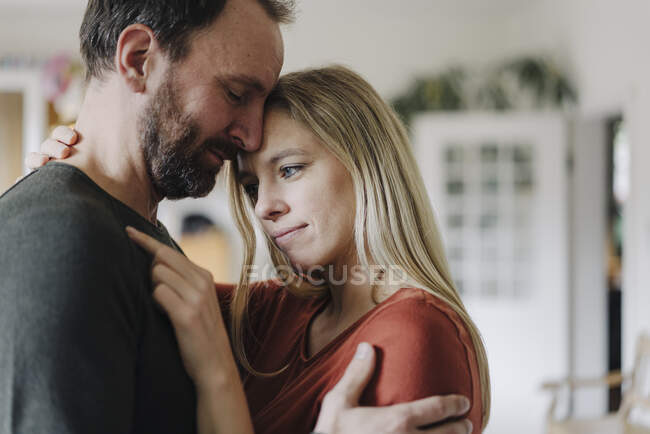 Feliz pareja abrazándose en su cómodo hogar - foto de stock