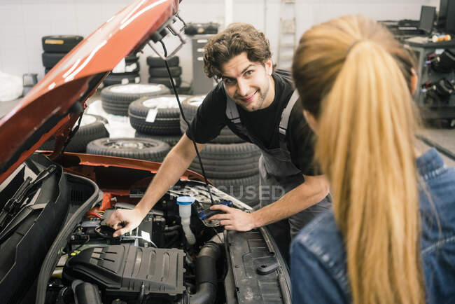 Kfz-Mechaniker schaut Kunde in Werkstatt an — Stockfoto