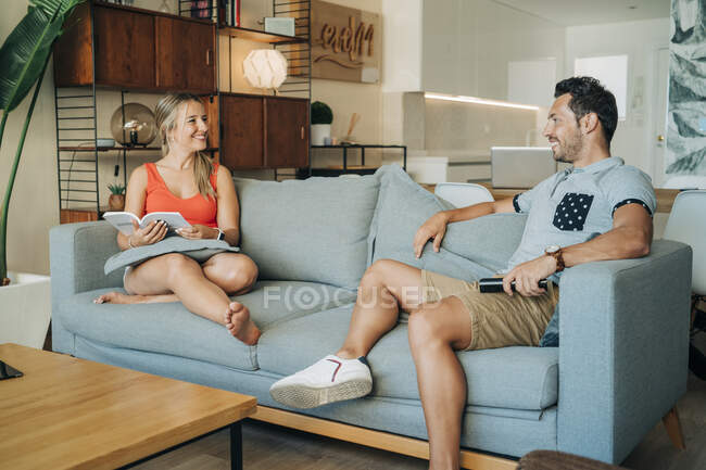 Casal feliz sentado no sofá na sala de estar — Fotografia de Stock