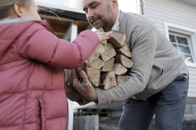 Чоловік носив дрова, дочка давала йому дерево. — стокове фото