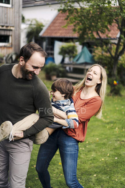 Padres e hijo divirtiéndose, jugando en el jardín - foto de stock