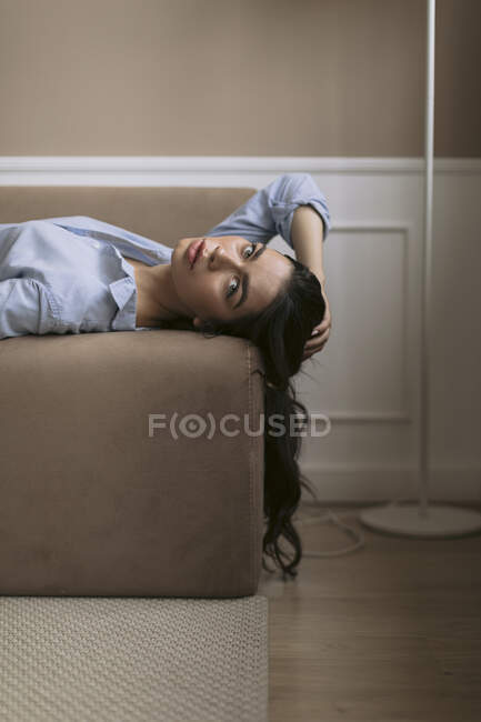 Retrato de una hermosa joven tumbada en el sofá en casa - foto de stock