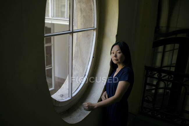 Retrato de mulher em pé ao lado da janela — Fotografia de Stock