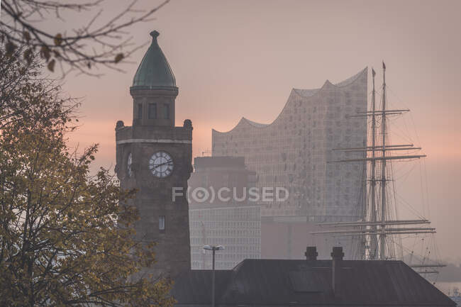 Germania, Amburgo, Landungsbrucken torre dell'orologio all'alba con Elbphilharmonie sullo sfondo — Foto stock