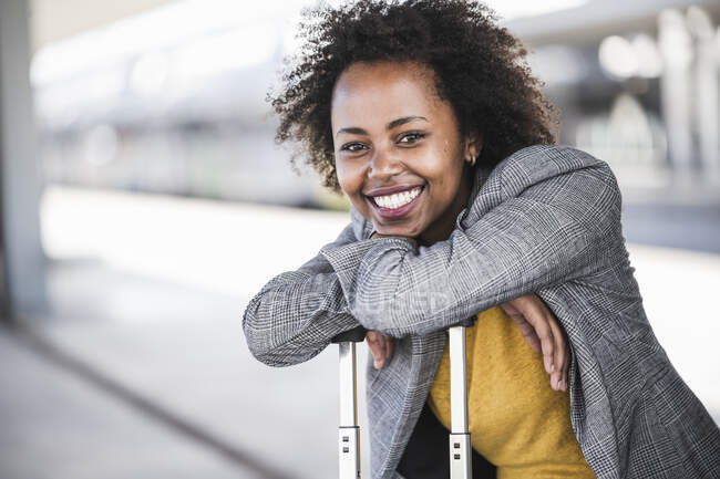 Ritratto di giovane donna d'affari sorridente con valigia alla stazione ferroviaria — Foto stock