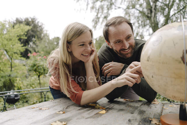 Pareja feliz planeando viajar, mirando el globo al aire libre - foto de stock