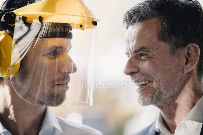 Усміхаючись, бізнесмен і чоловік у шоломі безпеки стоять один навпроти одного. — стокове фото
