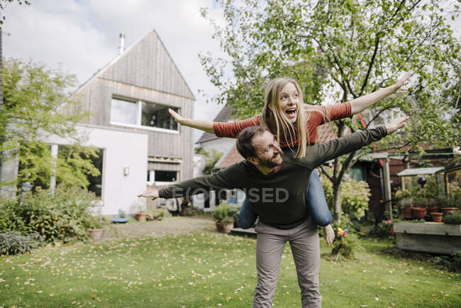 Acclamazione coppia fingendo di volare, in piedi nel loro giardino — Foto stock
