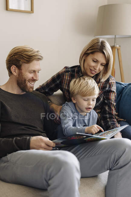 Familie schaut sich Buch zu Hause auf Couch an — Stockfoto