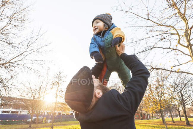 Homme soulevant son fils bébé heureux au parc — Photo de stock