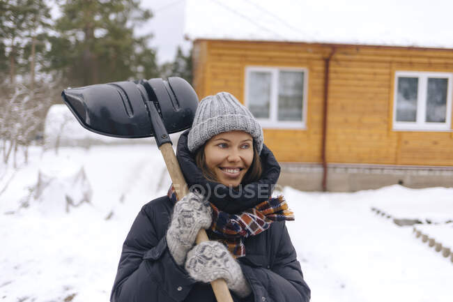 Портрет усміхненої жінки зі сніжною лопатою — стокове фото