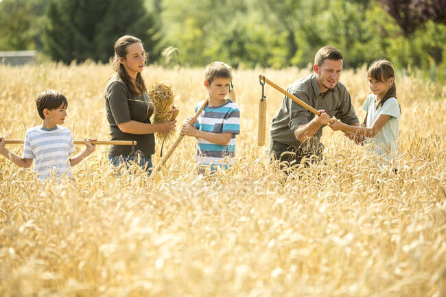 Children learning how to flail wheat in field — Stock Photo