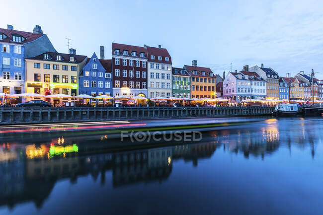 Denmark, Copenhagen, Light trails in front of row of colorful residential buildings standing along Nyhavn harbor — Stock Photo