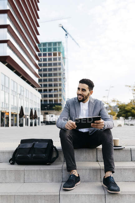 Casual jeune homme d'affaires assis sur les escaliers dans la ville en utilisant une tablette — Photo de stock