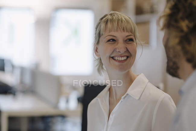Portrait of smiling businesswoman looking at businessman in offce — Stock Photo