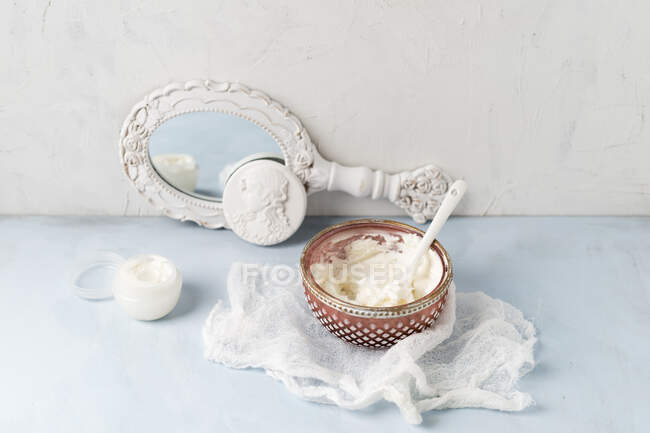 Gauze, hand mirror and bowl of homemade shea butter moisturizer — Stock Photo