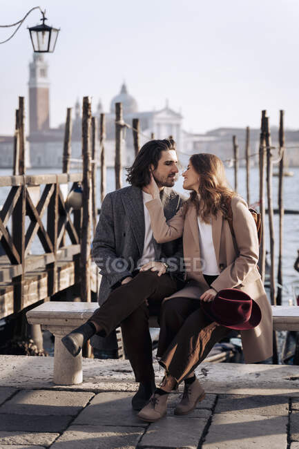 Молодая пара сидит на набережной в Венеции, Италия — стоковое фото