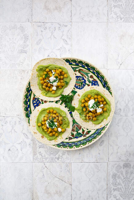 Teller Fladenbrot mit pürierten Avocados, Kurkuma-Kichererbsen, Joghurt und Petersilie — Stockfoto