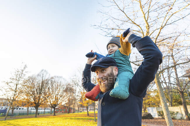 Uomo felice che porta il suo bambino sulle spalle al parco — Foto stock