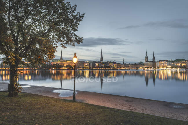 Germania, Amburgo, Edifici sul lungomare che si riflettono nel lago Inner Alster all'alba — Foto stock