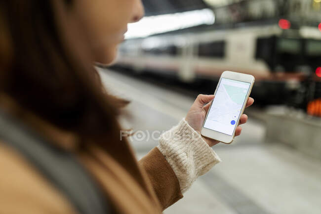 Primer plano de la mujer usando el teléfono celular en la estación de tren - foto de stock