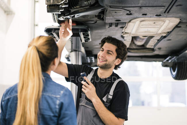 Car mechanic talking to client in workshop — Stock Photo