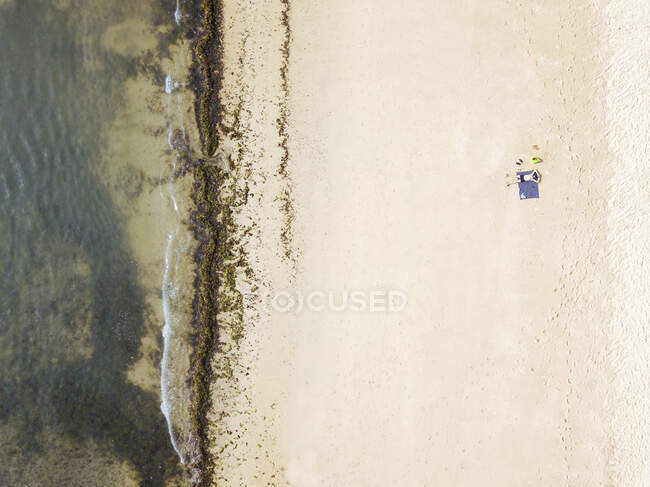 Indonesia, Bali, Vista aérea del hombre tomando el sol en la playa costera de arena de Nusa Dua - foto de stock