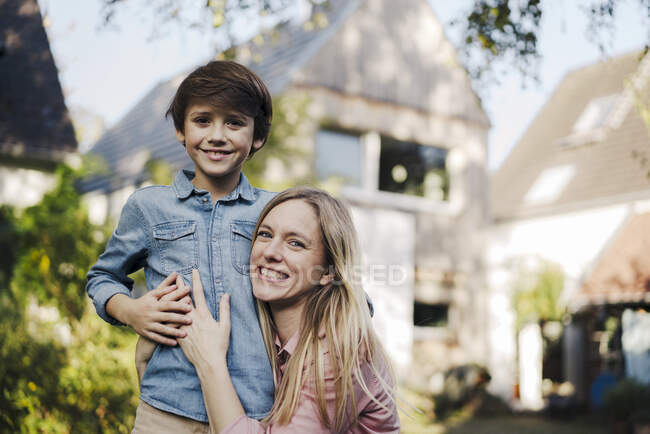 Mother embracing son in the garden of their home — Stock Photo