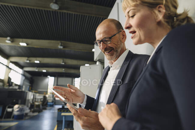 Homme d'affaires et femme d'affaires utilisant une tablette dans une usine — Photo de stock