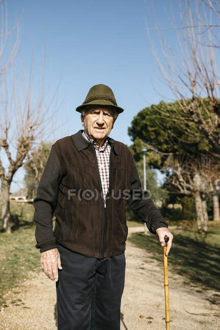 Viejo caminando en el parque de invierno, apoyado en su acné - foto de stock