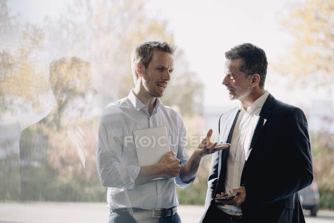 Dos hombres de negocios hablando por la ventana - foto de stock