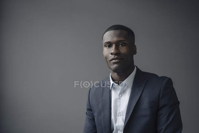 Portrait of young businessman against grey background — Stock Photo