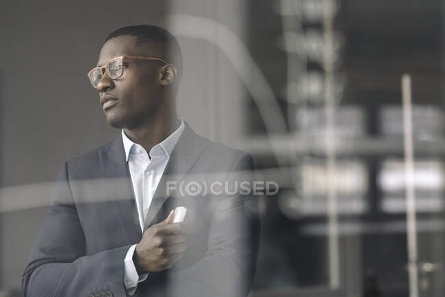 Porträt eines jungen Geschäftsmannes hinter einer Glasscheibe im Büro — Stockfoto