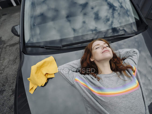 Рыжая женщина лежит на капоте автомобиля — стоковое фото