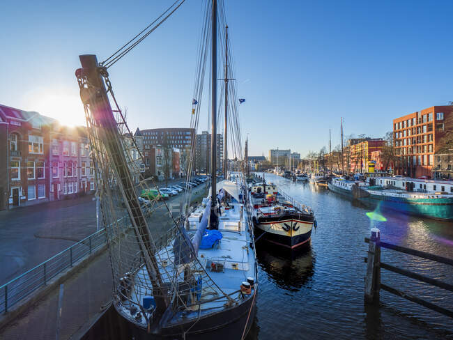 Niederlande, Friesland, Groningen, Jachthaven Oosterhaven, Stadt und Boote, die bei Sonnenuntergang am Kanal festmachen — Stockfoto