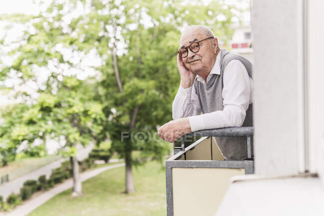 Ritratto di uomo anziano sorridente in piedi sul balcone — Foto stock