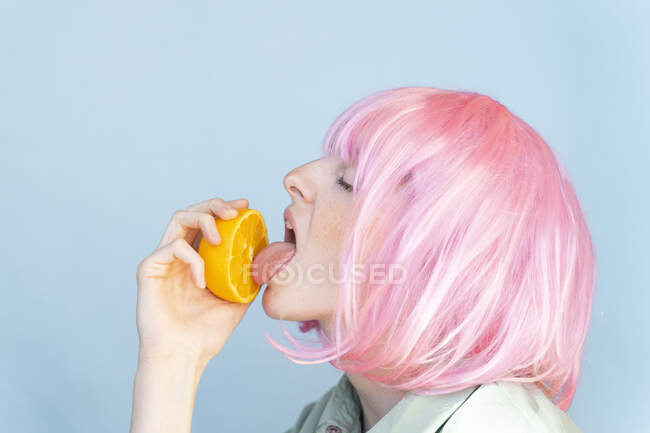 Jovem mulher vestindo rosa peruca lambendo um ornamento — Fotografia de Stock