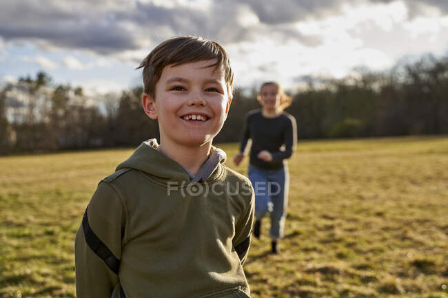 Porträt eines glücklichen Jungen mit Schwester auf einer Wiese — Stockfoto