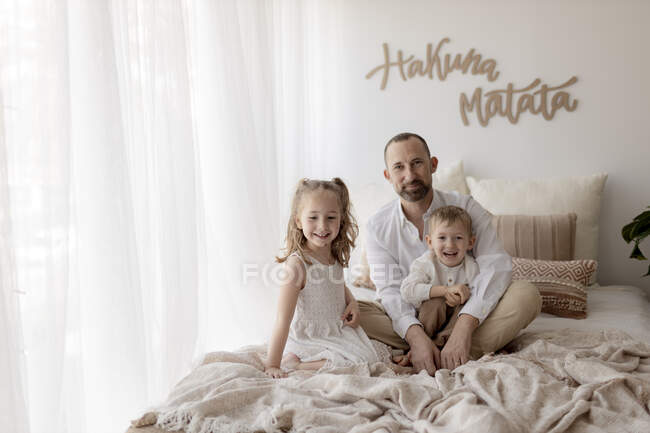 Сімейний портрет щасливого батька з двома дітьми, які сиділи разом на ліжку. — стокове фото